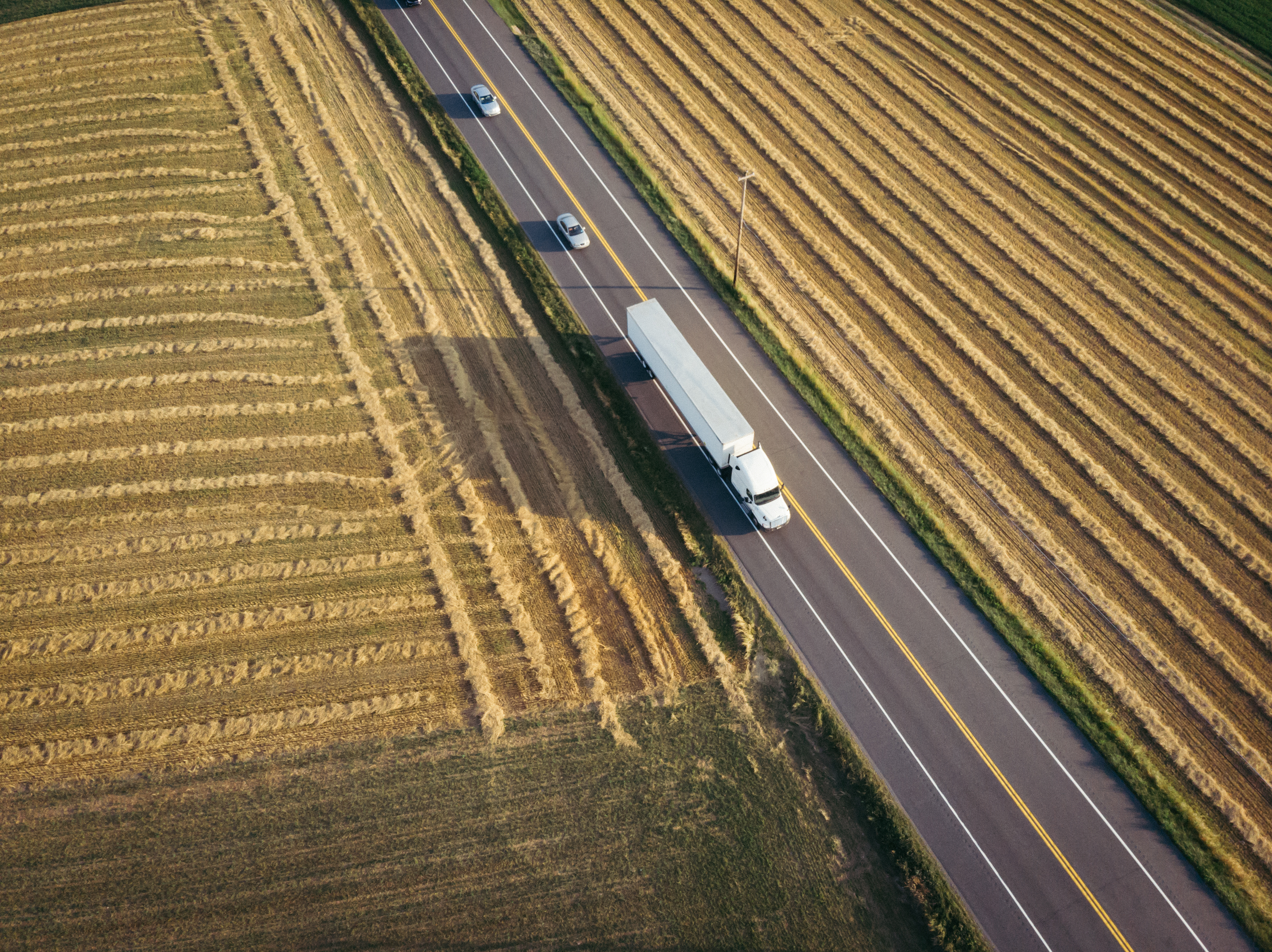 Aerial of a delivery truck on a road through farmland