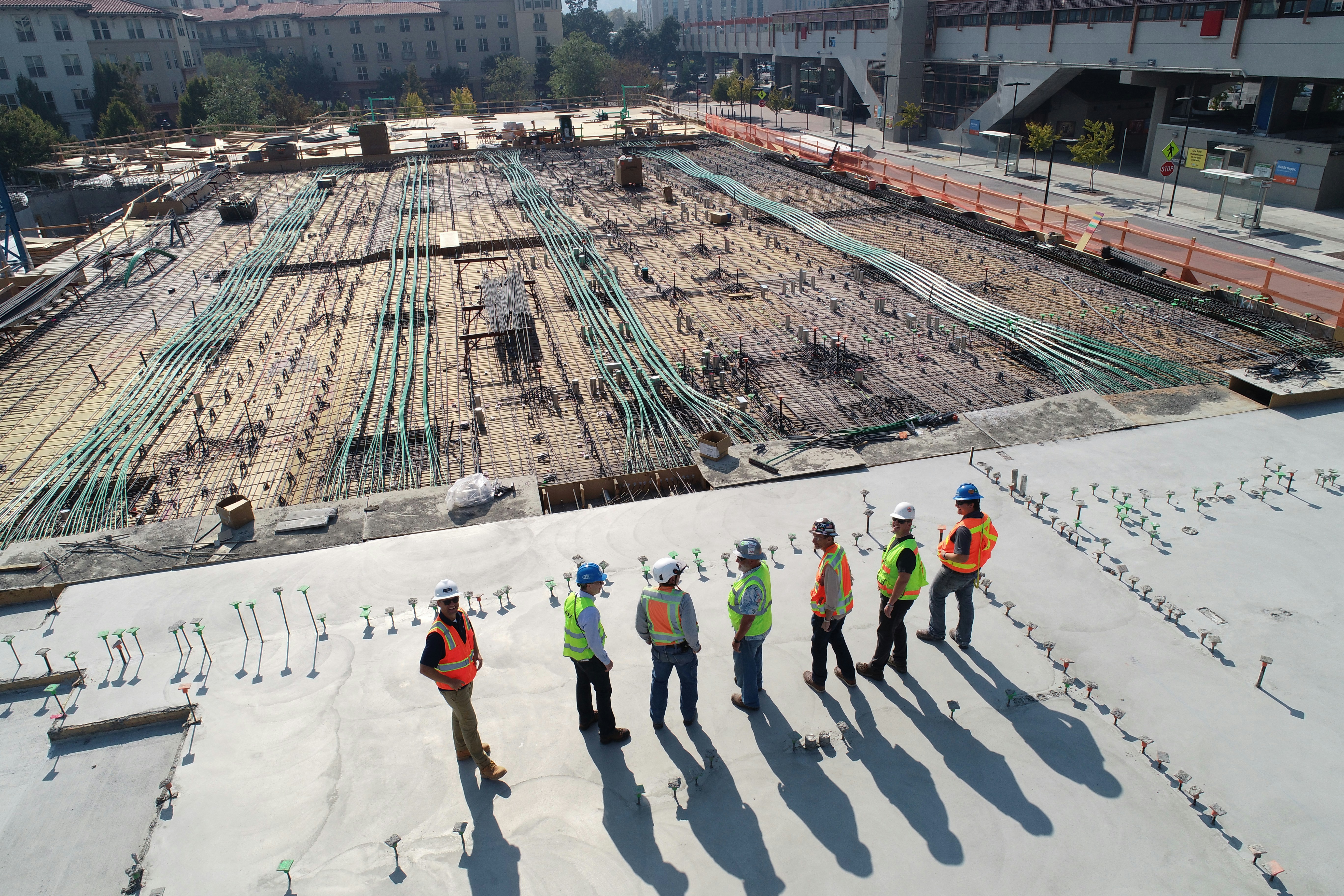 Construction crew surveying a large building site from a rooftop